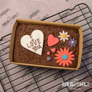 A brownie slab with I Love You piped and some hearts and flowers